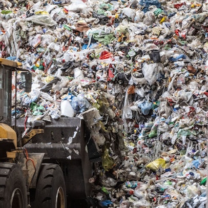 Ein Radlader bewegt angelieferten Verpackungsmüll in einer Sortieranlage.