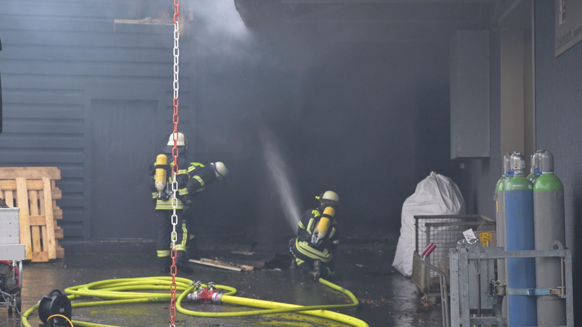 Feuerwehrleute löschen einen Brand in einer Gewerbehalle am Rösrather Pestalozziweg.