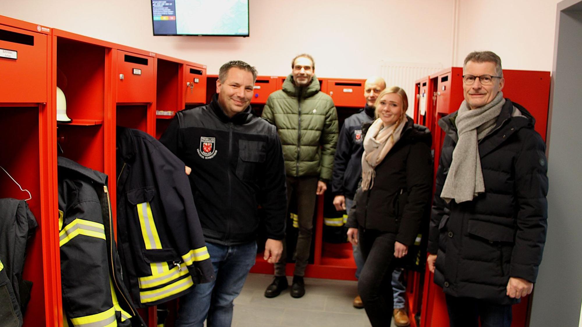 Vier Männer und eine Frau stehen im neuen Umkleidebereich des Feuerwehrgerätehauses in Dahlem-Schmidtheim. In roten Spinden ist die Einsatzkleidung der Feuerwehrleute.