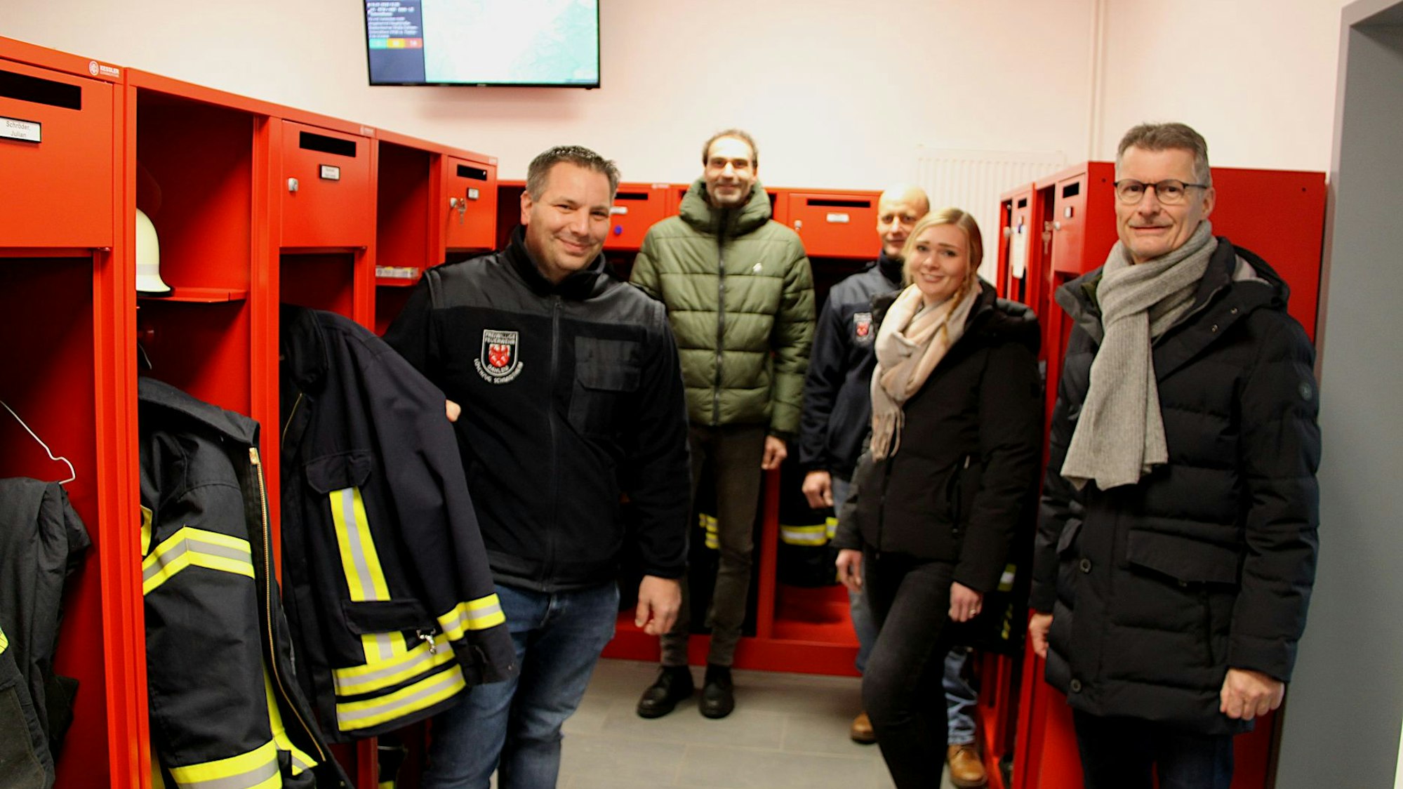 Vier Männer und eine Frau stehen im neuen Umkleidebereich des Feuerwehrgerätehauses in Dahlem-Schmidtheim. In roten Spinden ist die Einsatzkleidung der Feuerwehrleute.