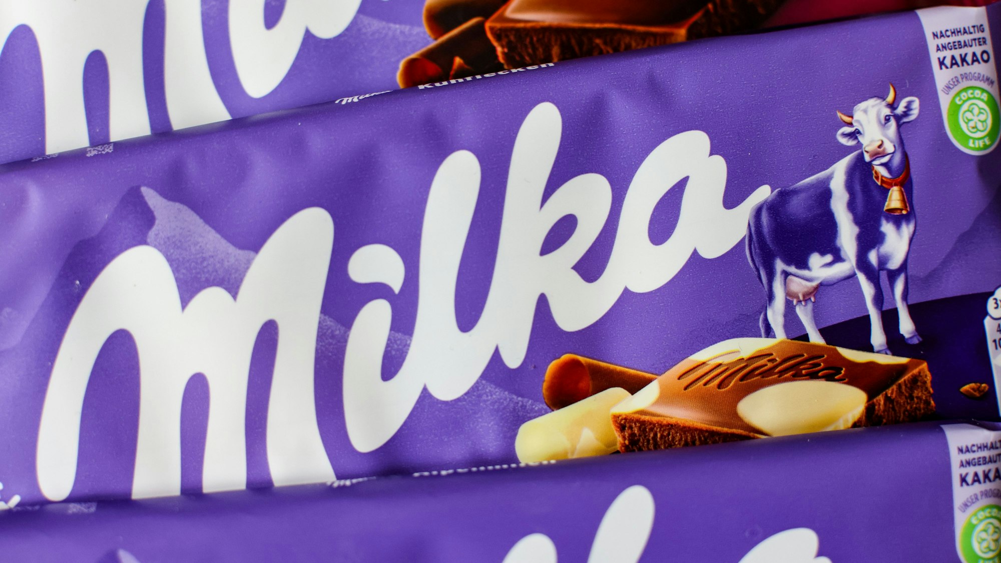 Drei Tafeln Milka-Schokolade liegen auf einem Tisch.