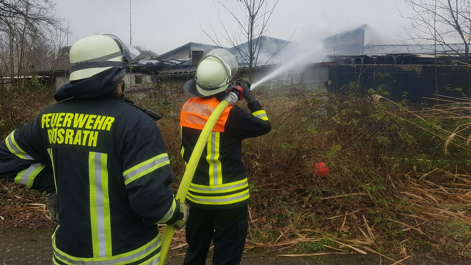 Zwei Feuerwehrmänner löschen mit einem C-Rohr.