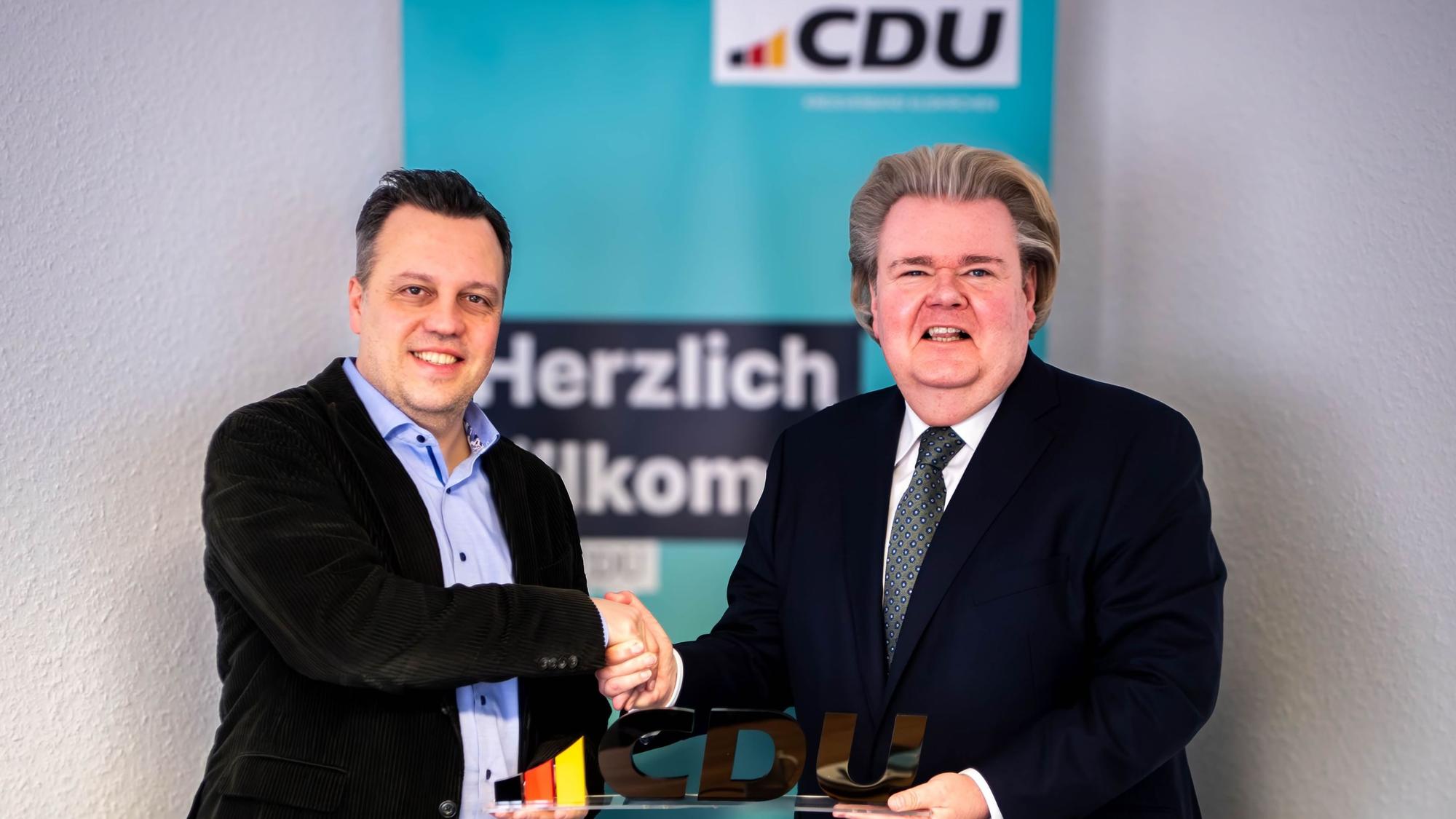 Das Bild zeigt Sacha Reichelt und Klaus Voussem, die die Zusammenarbeit mit einem Handschlag besiegeln