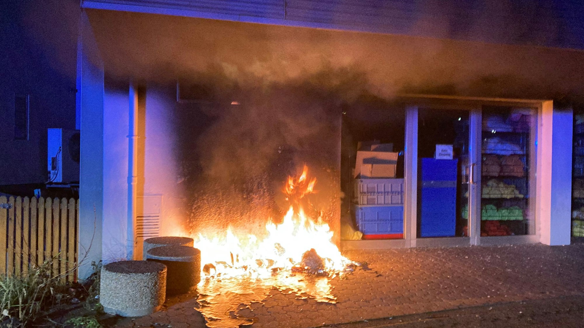 Vor einem Haus brennt eine Mülltonne.