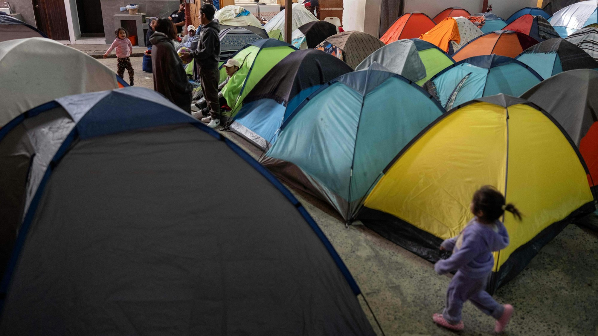 Ein Mädchen läuft bei Dunkelheit zwischen dicht gedrängten Zelten entlang.