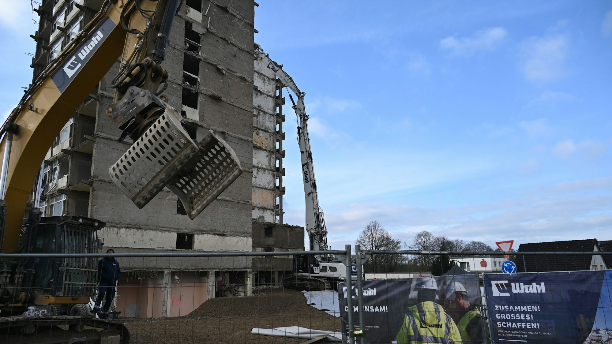 Zu sehen sind Bagger vor einem Hochhaus, das abgebrochen wird.