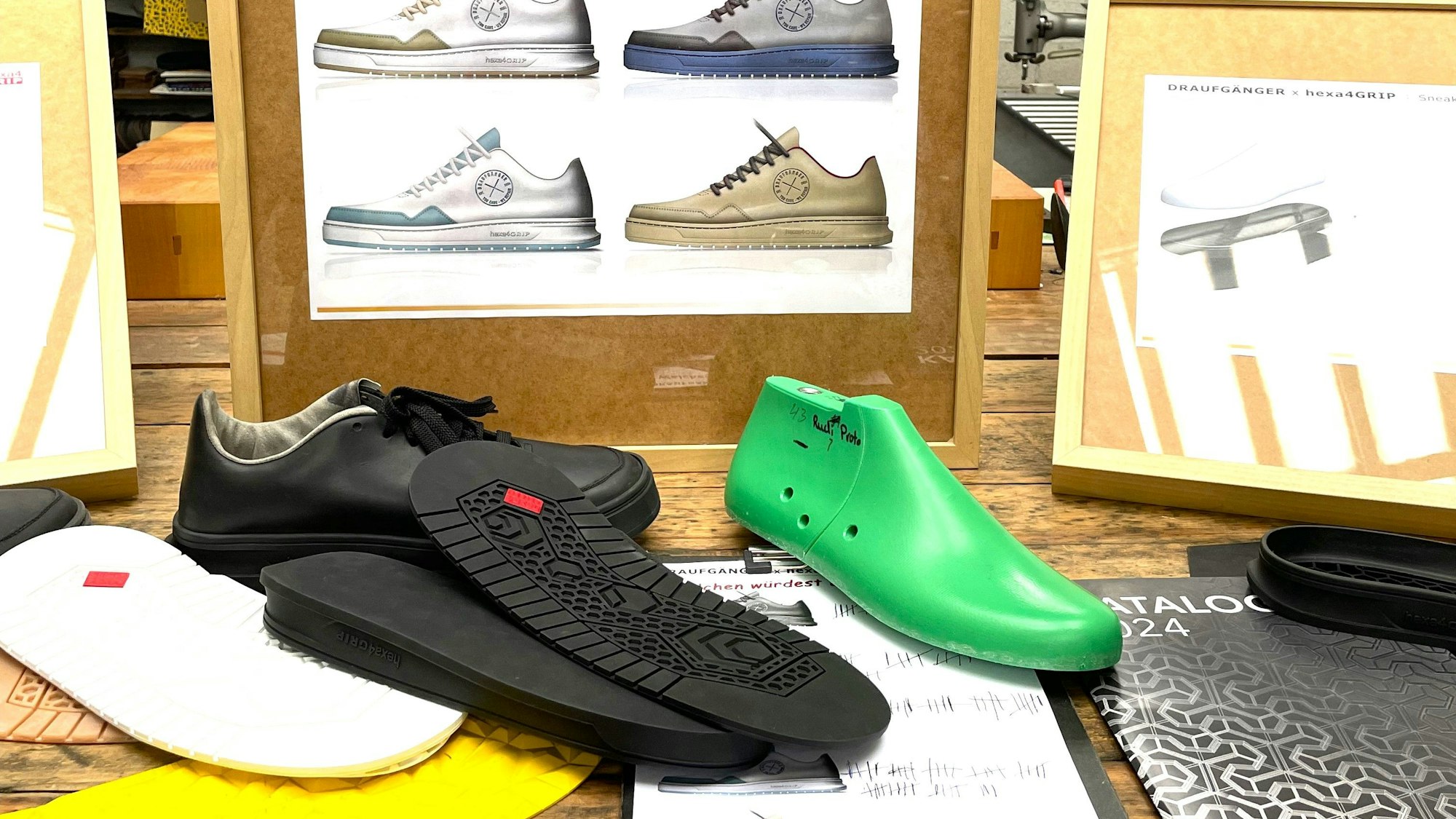 Schuhsohlen und ein Leisten liegen auf einem Tisch, auf dem ein Bild steht, das vier verschiedene Turnschuh-Modelle zeigt.