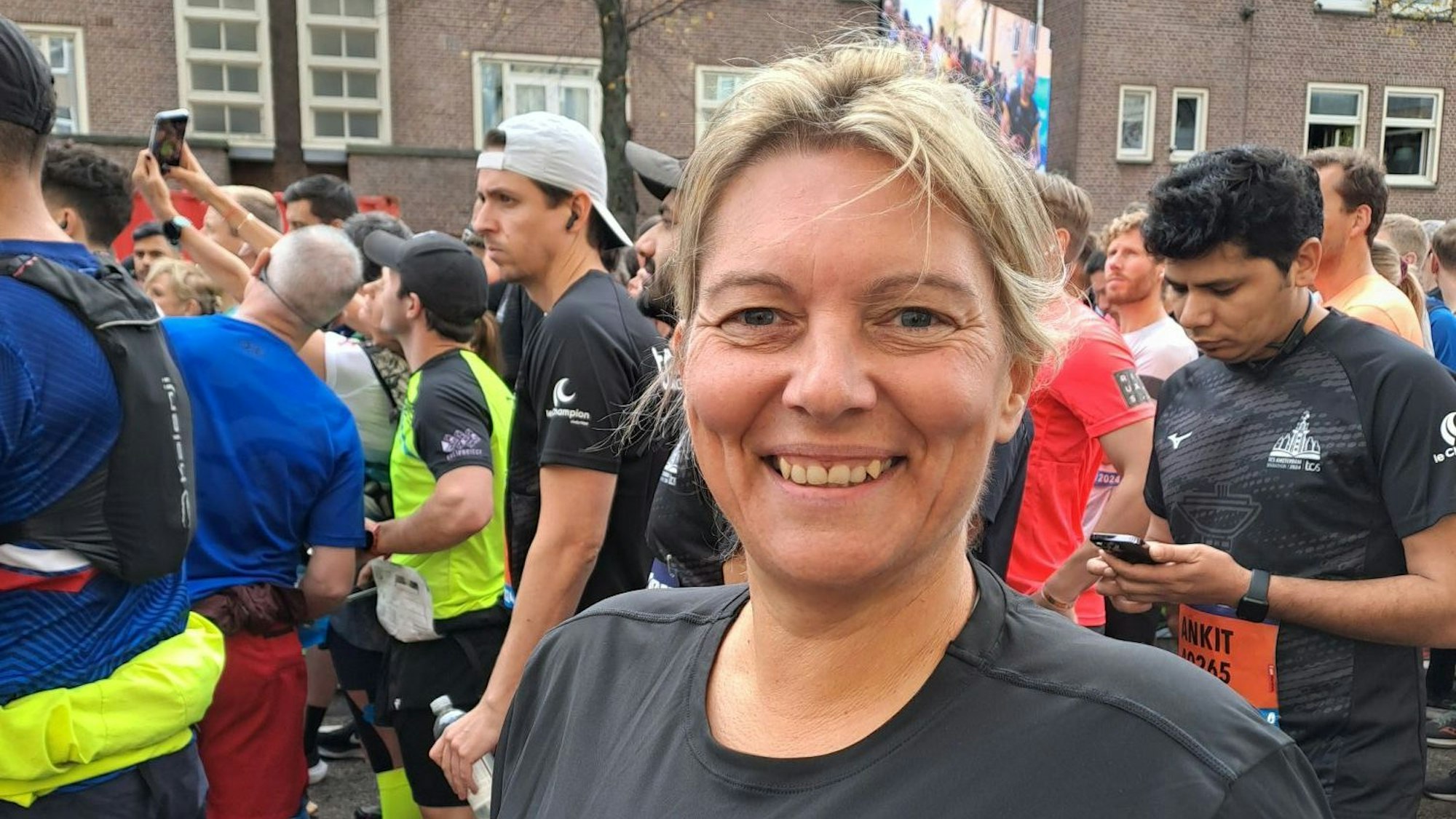 Ilona Schaffrath steht im Starterfeld einer Laufveranstaltung und lacht in die Kamera.