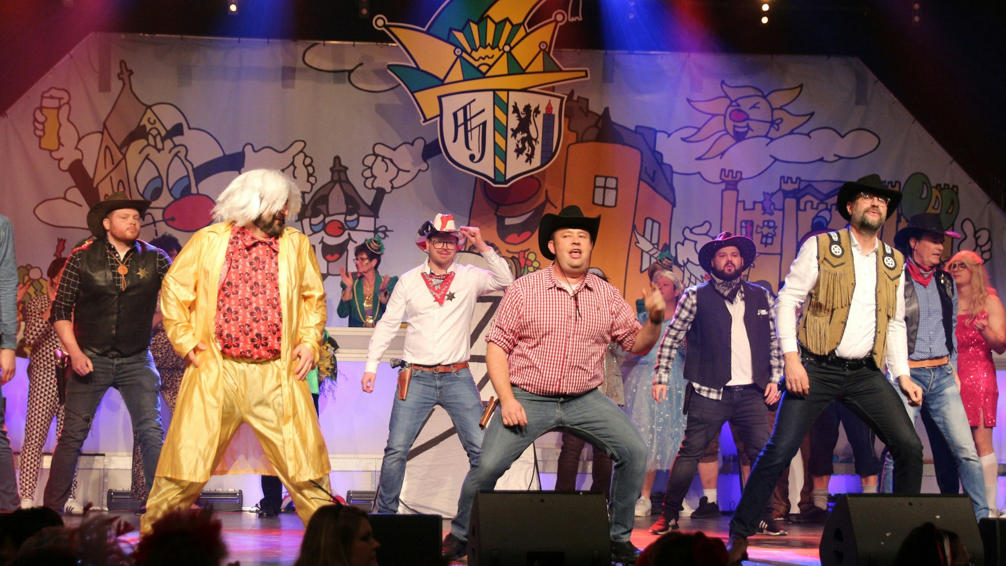 Männer, die als Cowboys verkleidet sind, stehen auf einer Bühne.