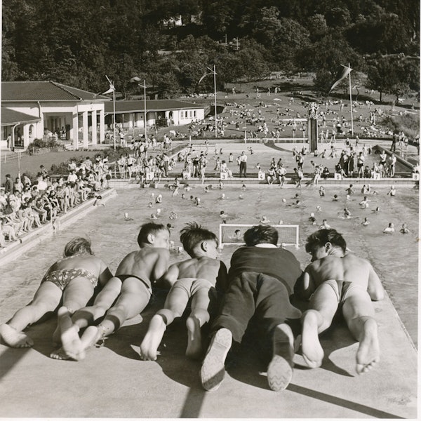 Kinder in Badehosen auf der Plattform eines Sprungturmes-