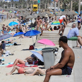 24.07.2024, Spanien, Palma: Touristen genießen einen warmen Sommertag am Strand von Arenal.