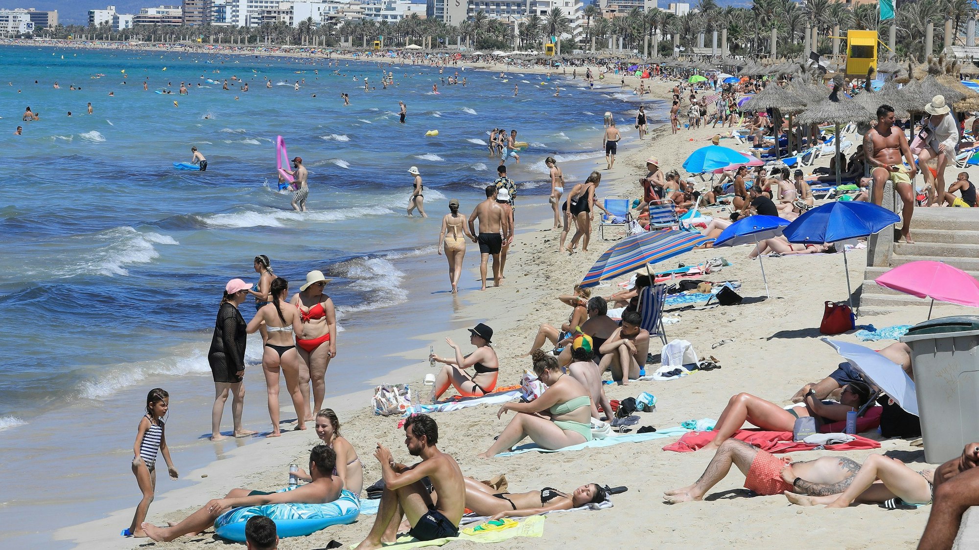 24.07.2024, Spanien, Palma: Touristen genießen einen warmen Sommertag am Strand von Arenal.