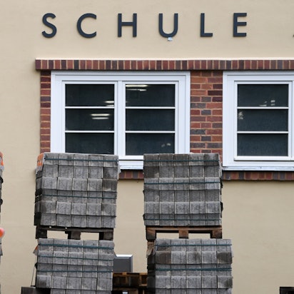 Zu sehen ist die Fassade eines Schulgebäudes. Davor steht Baumaterial.