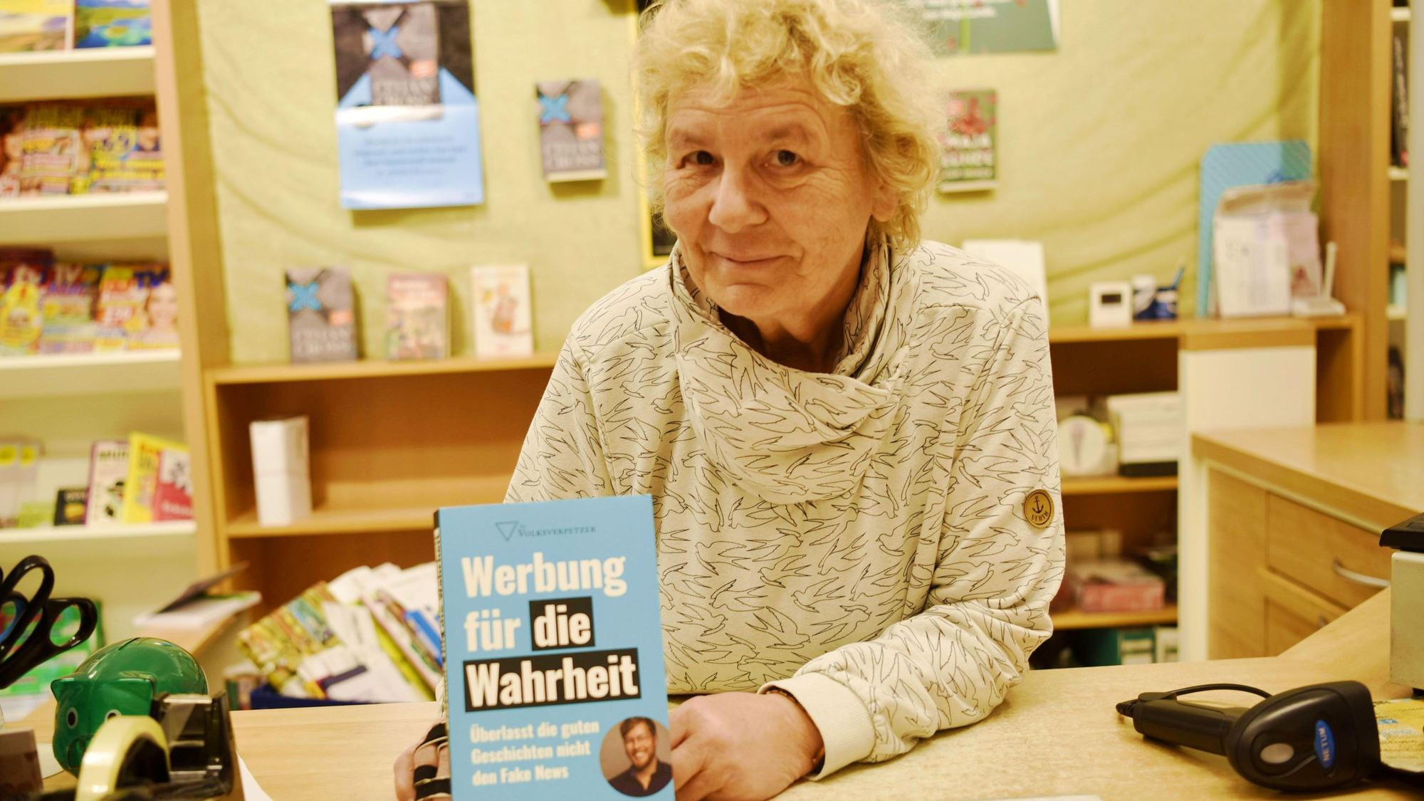 Buchhändlerin Claudia Reinhardt hält das Buch "Werbung für die Wahrheit" von Thomas Laschyk in die Kamera.