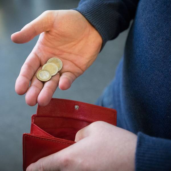 Münzen im Wert von fünf Euro werden in Paderborn über ein rotes Portemonnaie gehalten.
