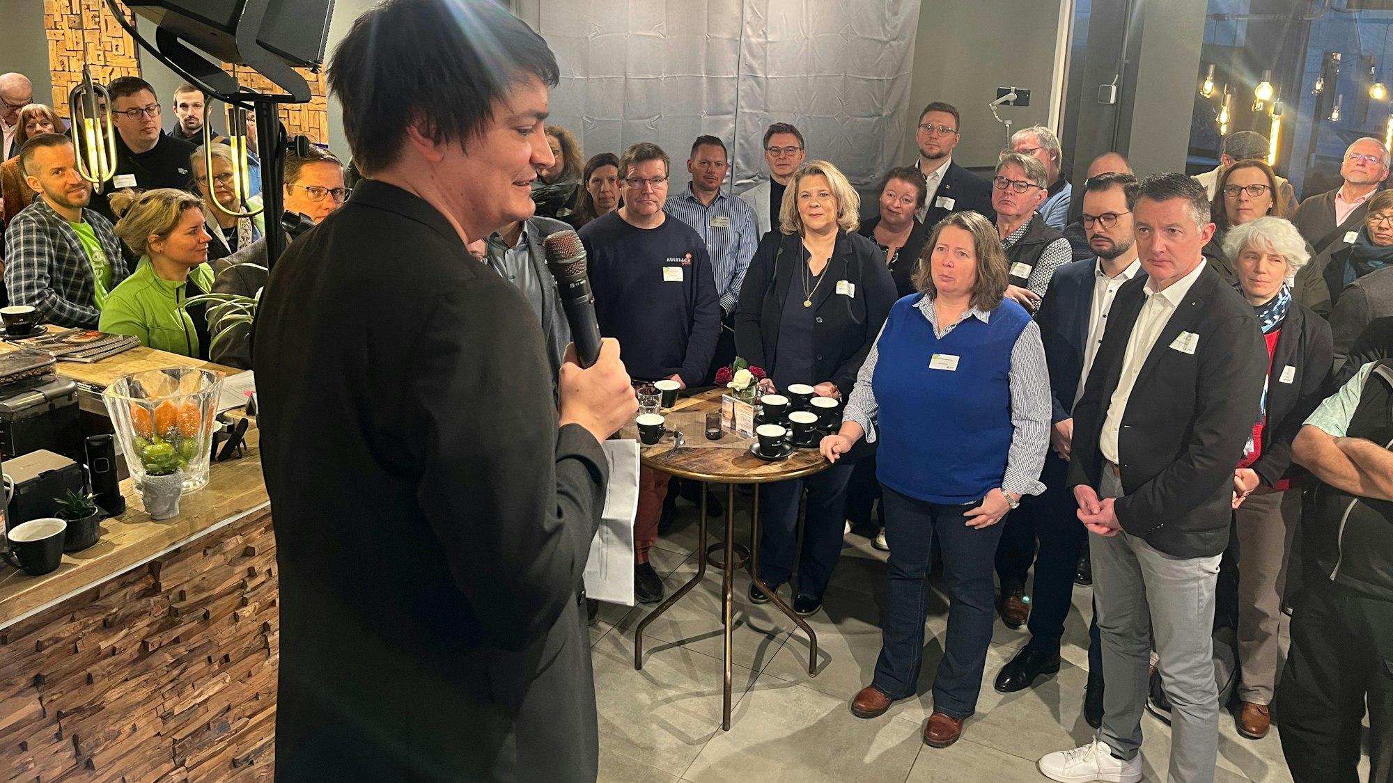 Ein Mann steht als Redner auf einer Bühne vor Publikum.