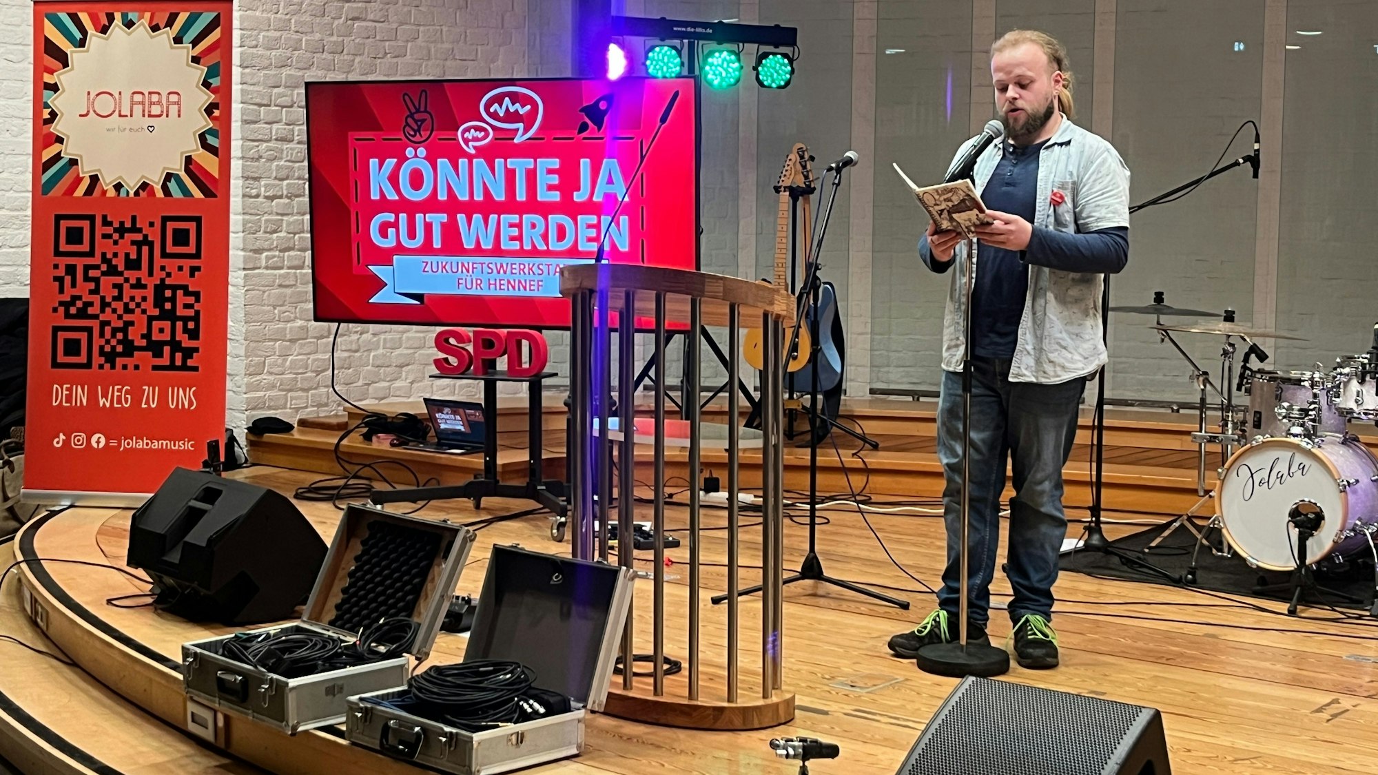 Ein Künstler steht zwischen Instrumenten auf einer Bühne.