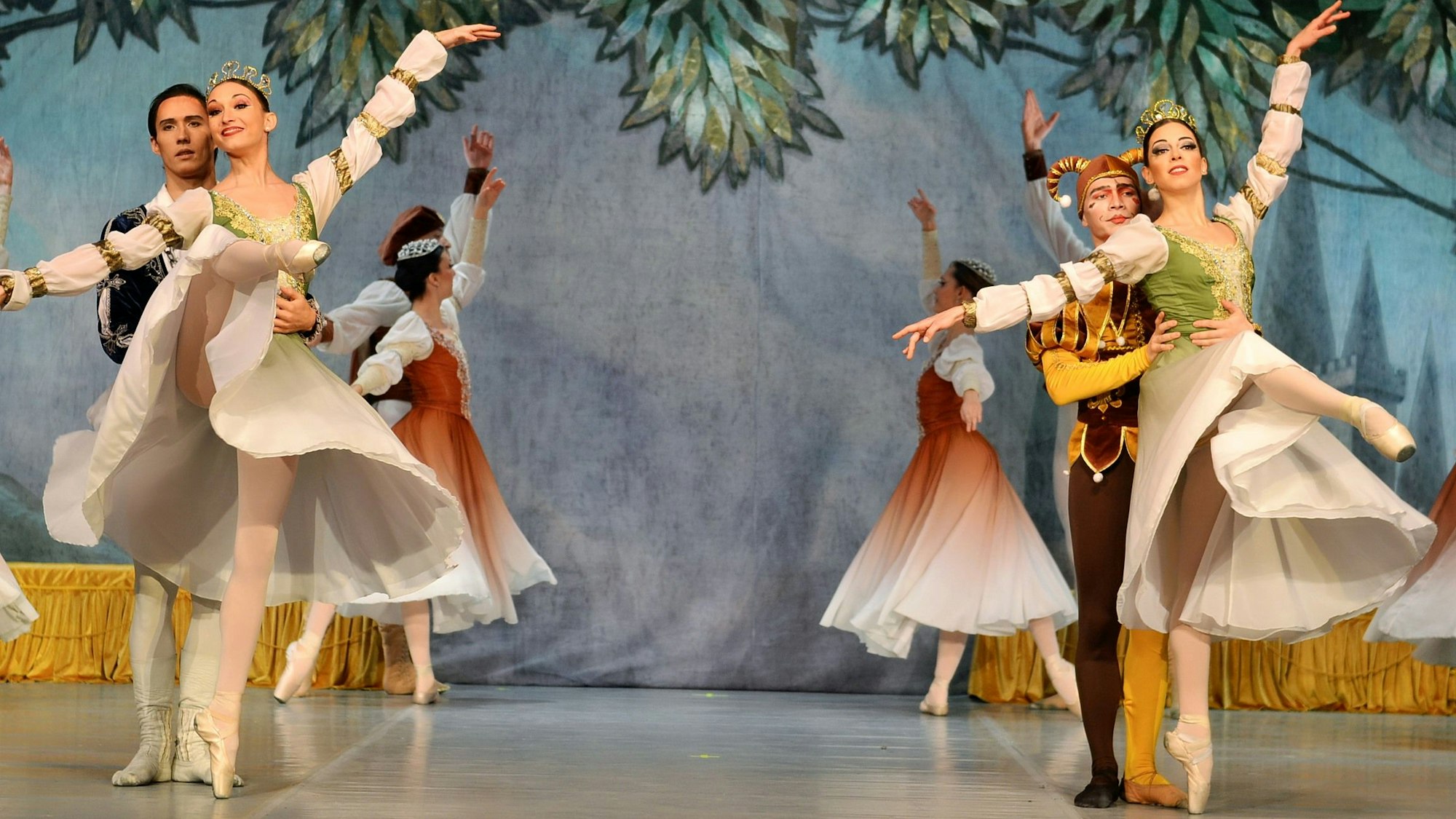 Zwei Tanzpaare tanzen in schönen Kleidern auf einer Bühne.