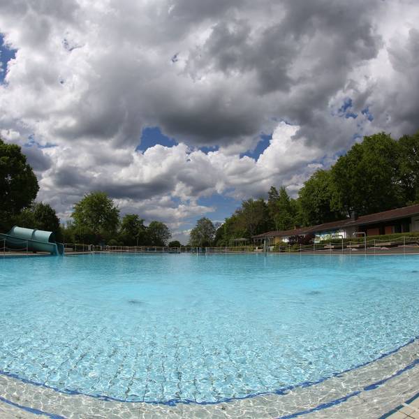 Ein großes Schwimmbecken, darüber dunkle Wolken am Himmel