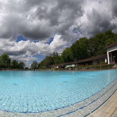 Ein großes Schwimmbecken, darüber dunkle Wolken am Himmel