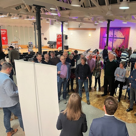 Eine Gruppe von Menschen steht zusammen und diskutiert.