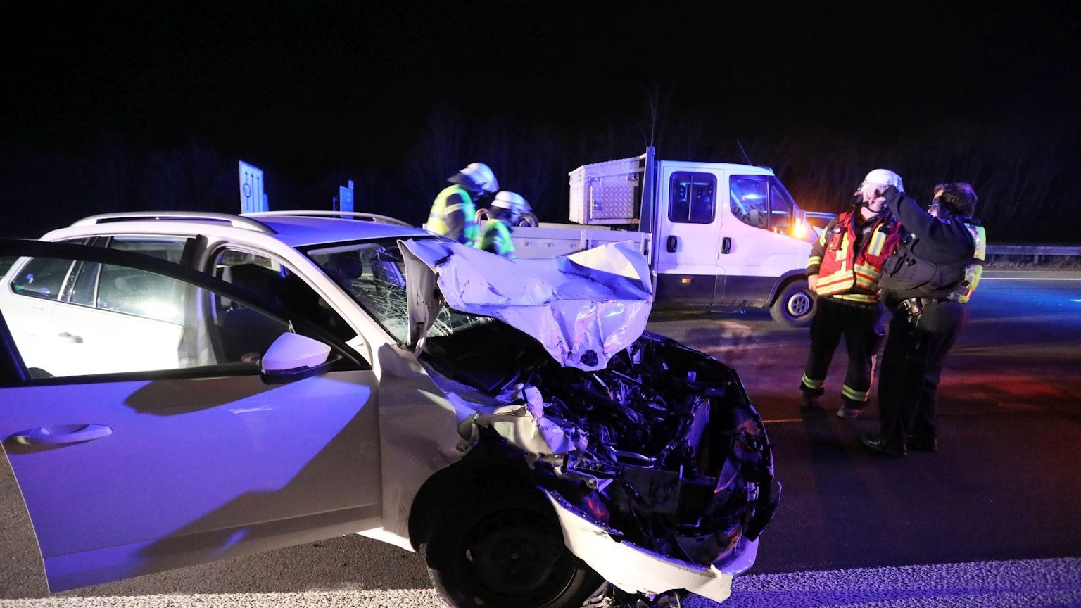 Feuerwehrleute stehen neben einem Auto mit demolierter Front