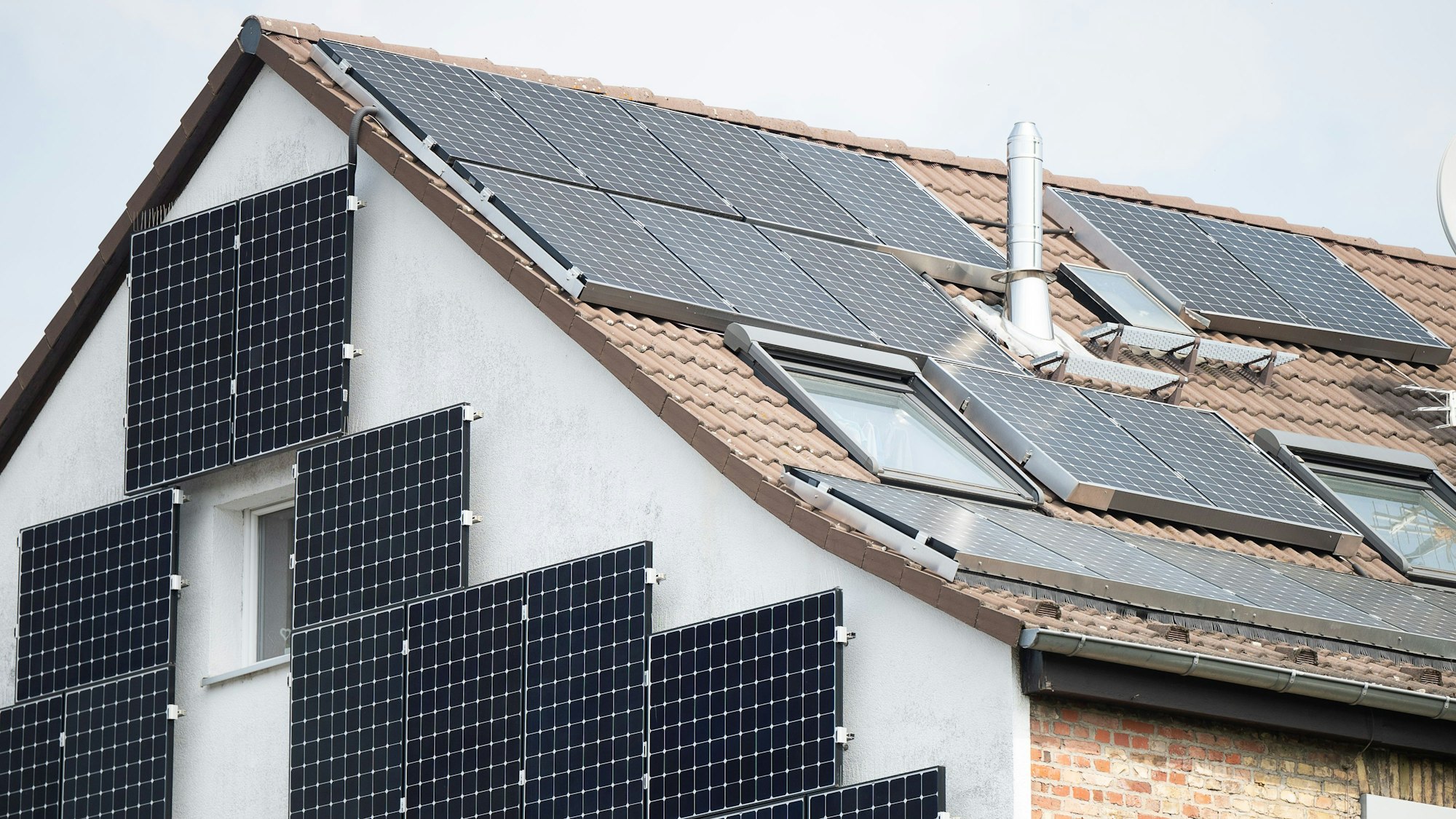 Solarpanel sind an der Fassade und auf dem Dach eines Hauses befestigt.