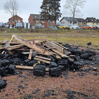 Auf dem Bild ist ein Haufen alter Bretter, die zum Teil verbrannt sind, zu sehen.