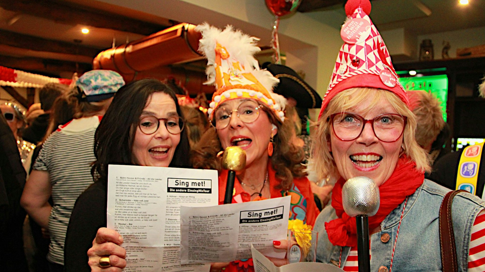 Drei Frauen halten Textblätter und singen.
