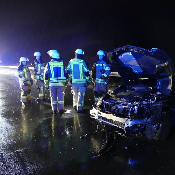Feuerwehrleute in der Nacht neben einem stark beschädigten PKW.