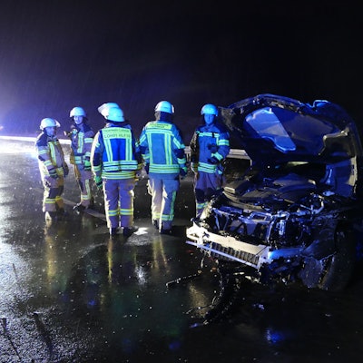 Feuerwehrleute in der Nacht neben einem stark beschädigten PKW.