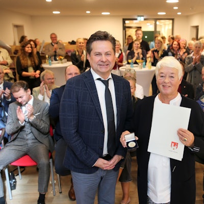 Ein Mann und eine Frau vor einer applaudierenden Menge.