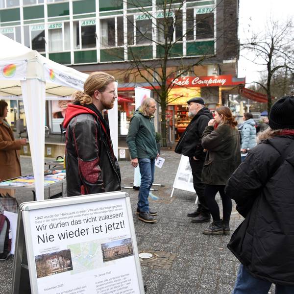 Menschen unterhalten sich vor einem Pavillon.