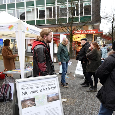 Menschen unterhalten sich vor einem Pavillon.