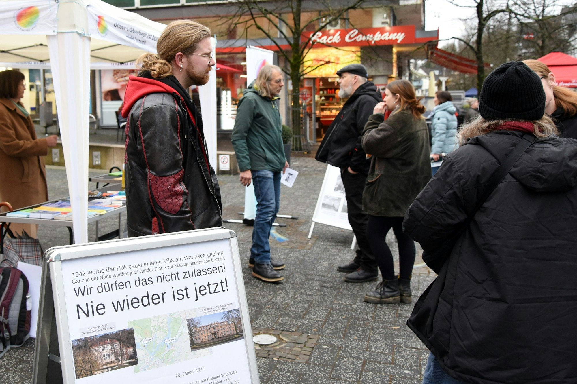 Menschen unterhalten sich vor einem Pavillon.