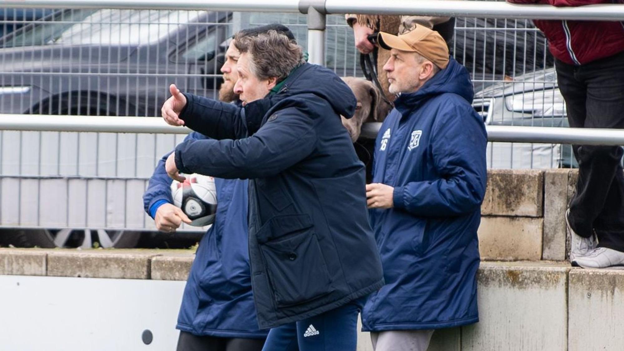 Das Spiel zeigt den Coach, der seine Spieler mit einer Geste in die Offensive treibt.