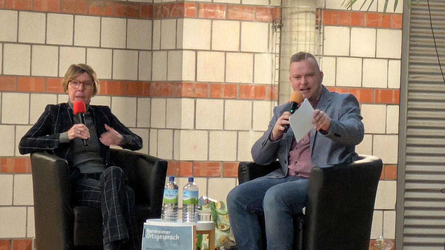 Bettina Böttinger sitzt auf der Bühne neben Dominik Pinsdorf.