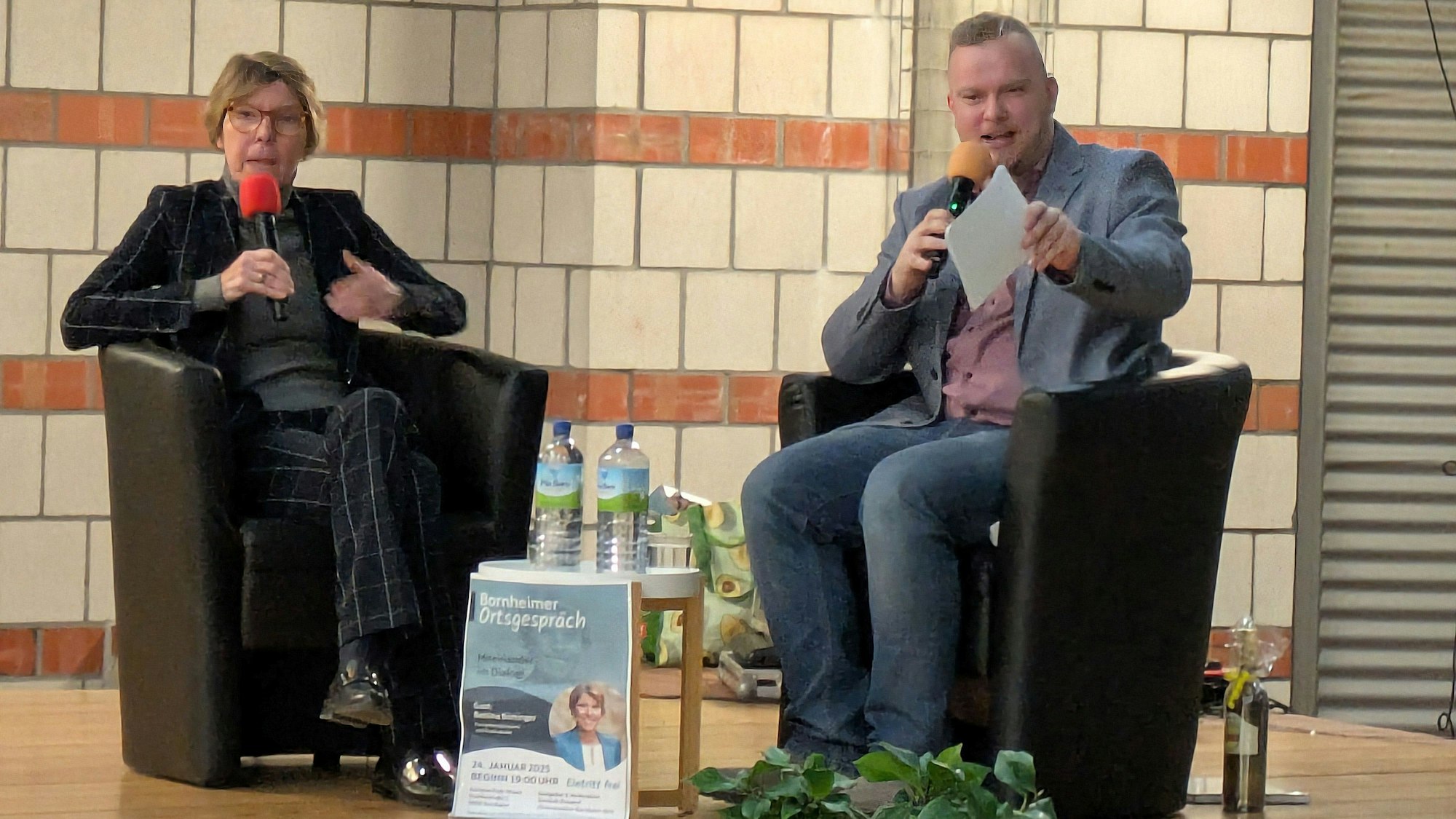 Bettina Böttinger sitzt auf der Bühne neben Dominik Pinsdorf.