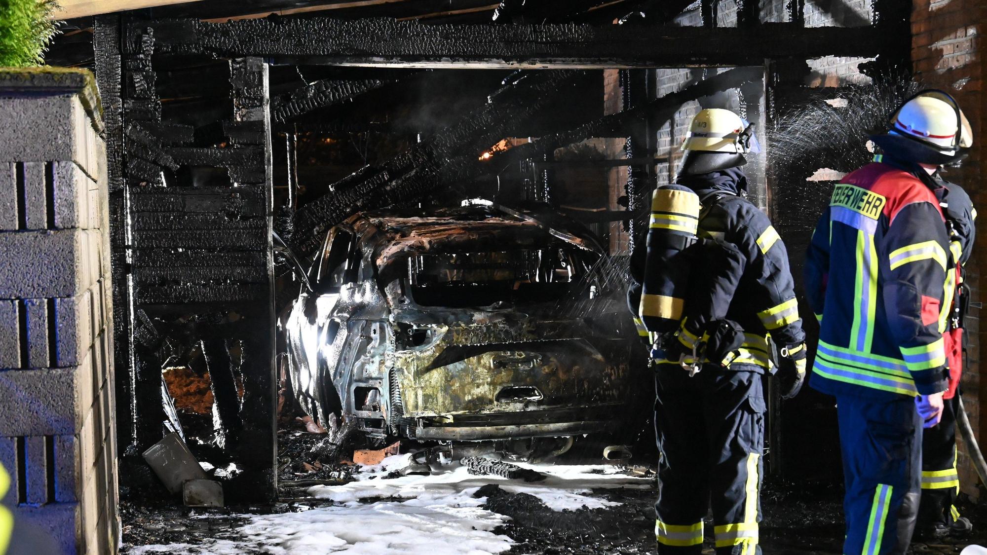 Eine abgebrannte Garage mit einem zerstörten Auto. Am Auto und auf dem Boden sind noch Reste des Löschschaums zu sehen.