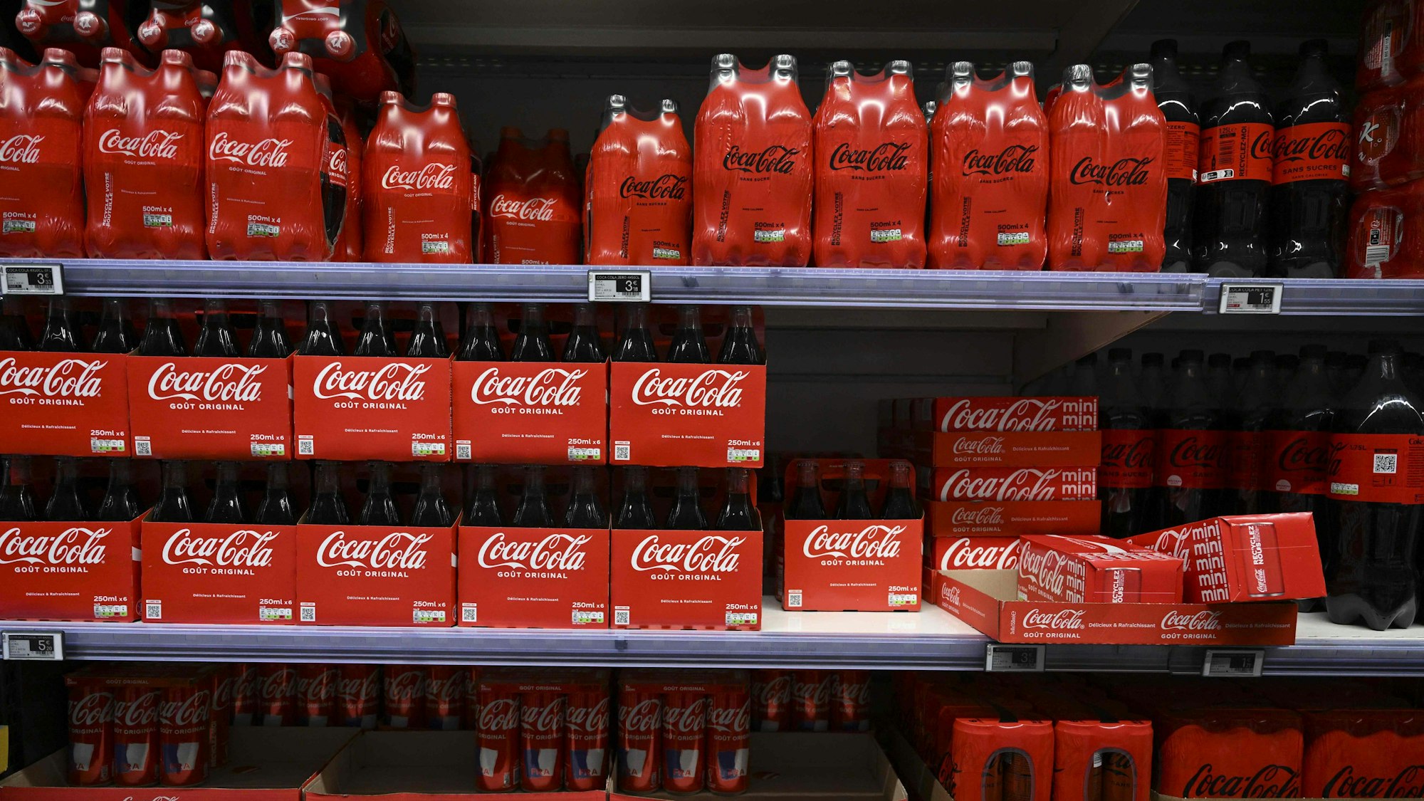 (FILES) This photograph taken on November 3, 2022 shows packs of Coca-Cola bottles on a supermarket shelf