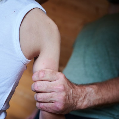 Ein Mann hält ein Kind fest am Arm (gestellte Szene).