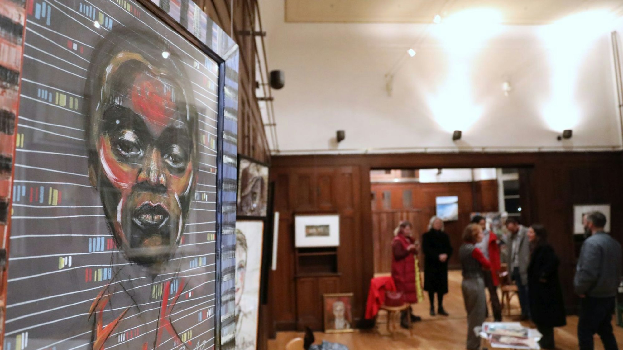 Ein großformatiges Porträt, im Hintergrund weitere Kunstwerke und Menschen, die sie betrachten.