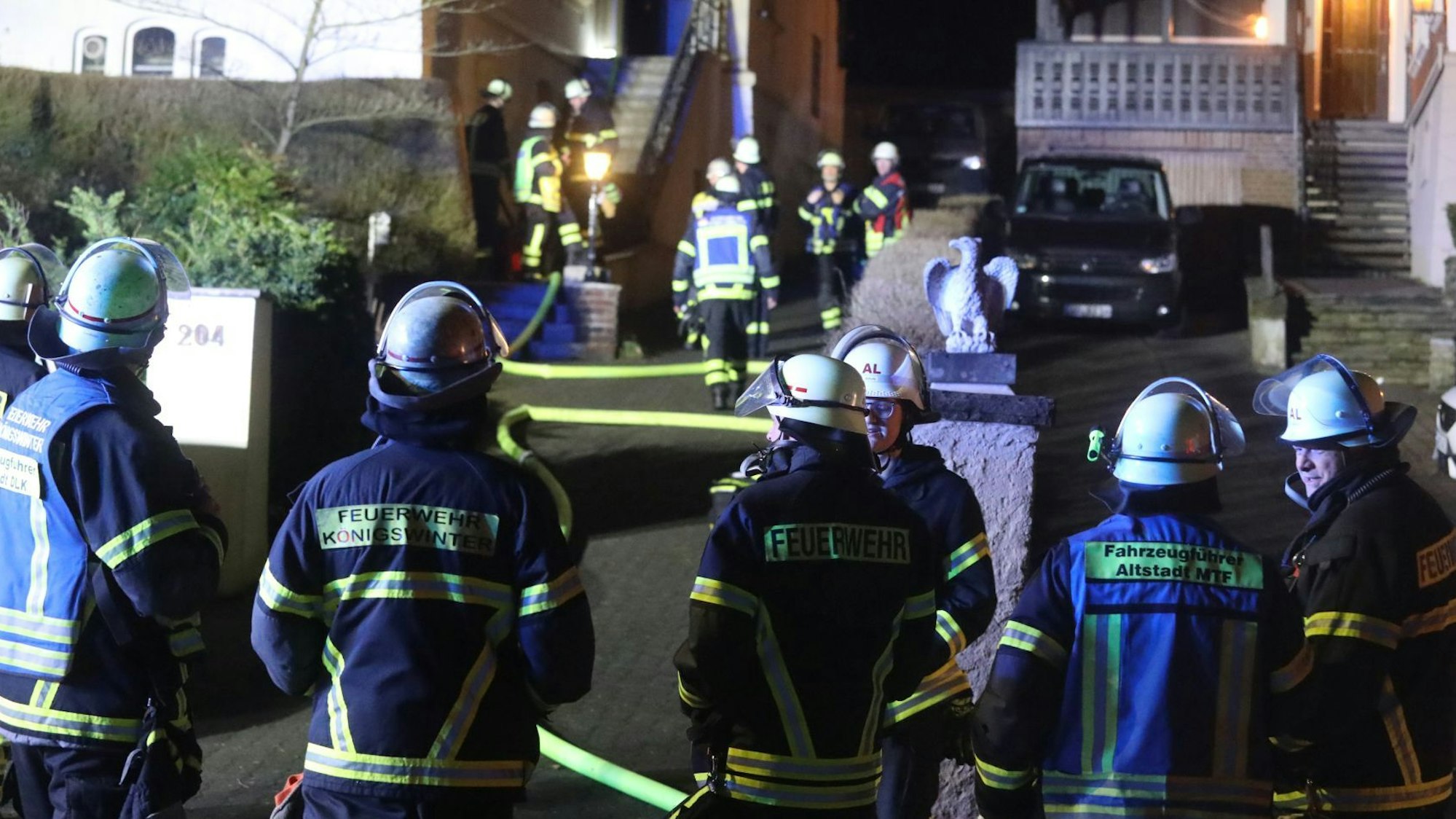 Feuerwehrleute stehen vor einem Mehrfamilienhaus.