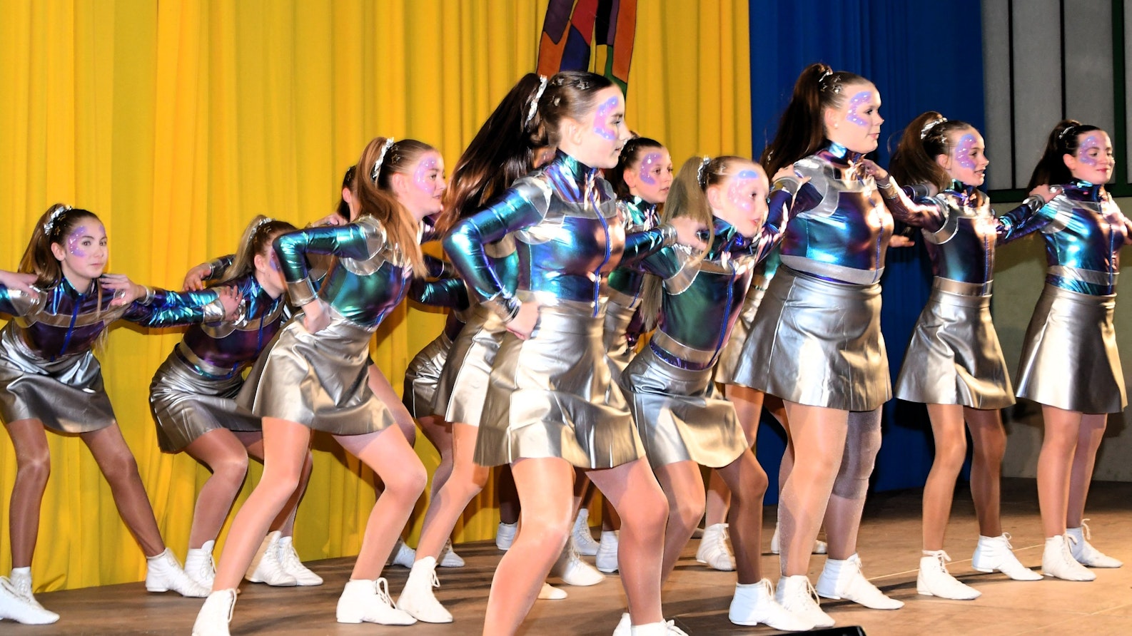 Eine Gruppe Mädchen in schillernden Kostümen tanzt auf der Bühne.