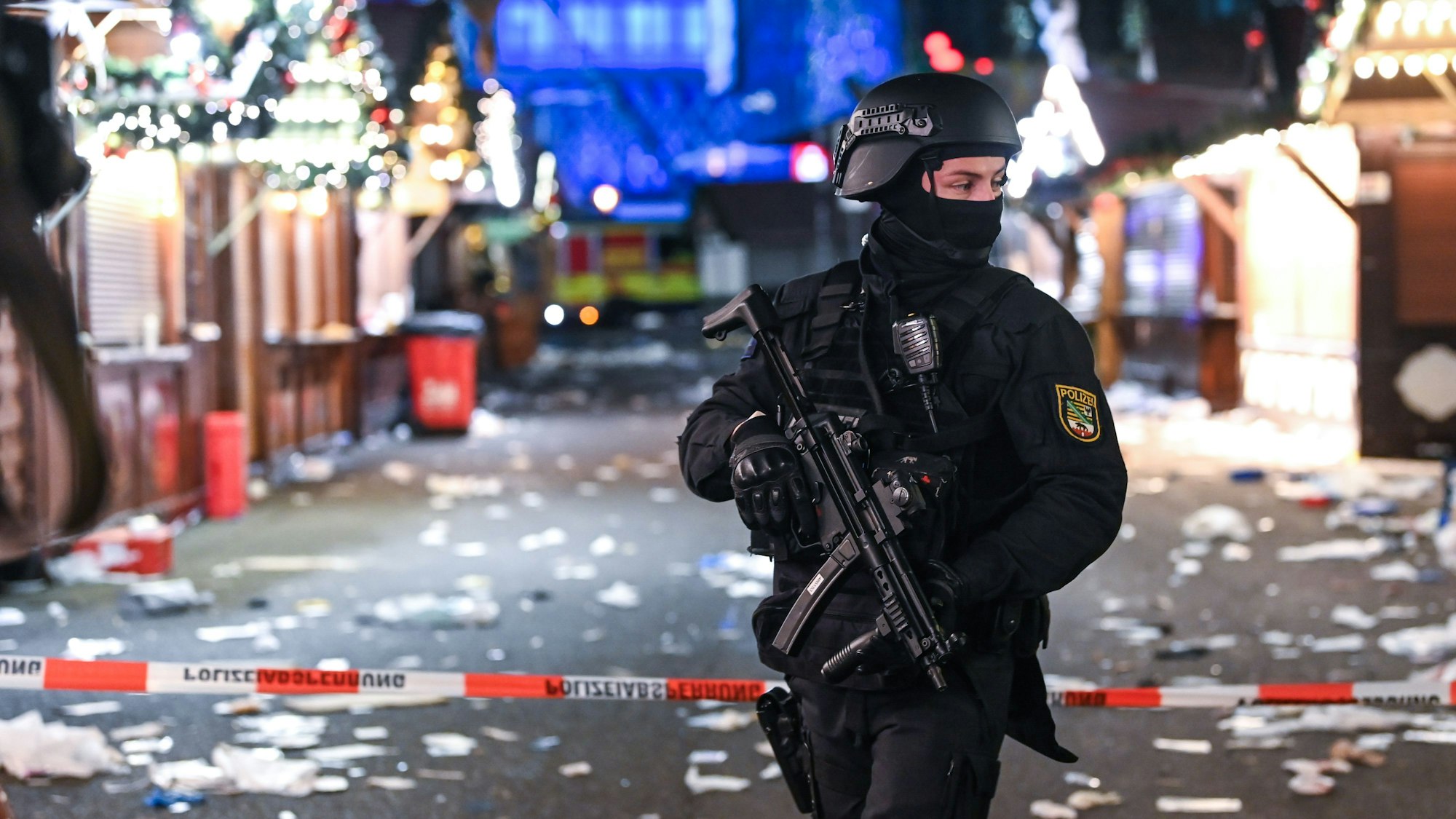 Ein schwer bewaffneter Polizist auf dem verwüsteten Weihnachtsmarkt in Magdeburg