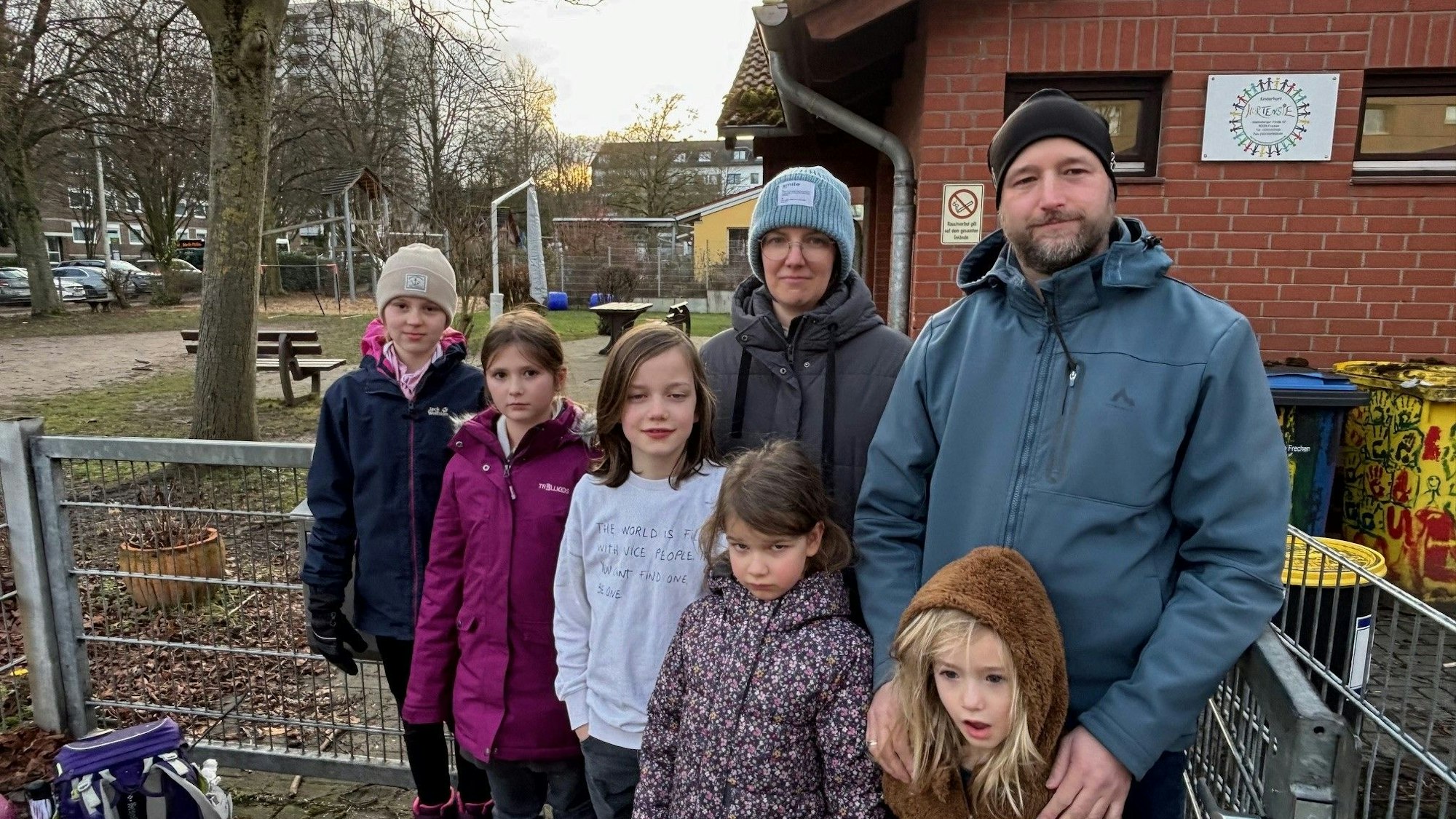 Eine Frau, ein Mann und Kinder stehen vor dem Hort, der geschlossen werden soll.