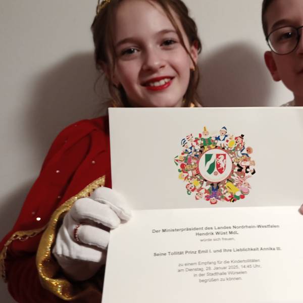 Das Kaller Kinderprinzenpaar Prinz Emil (Sträußl) und Prinzessin Annika (Pleuß) hält eine Einladung zum Empfang von Ministerpräsident Hendrik Wüst in den Händen.