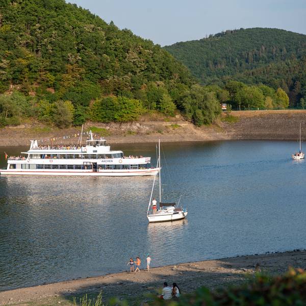 Auf dem Rursee fahren ein größeres Schiff und einige kleine Boote.