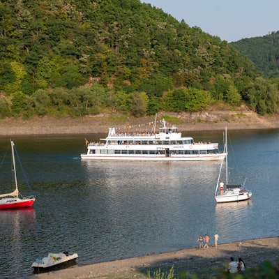 Auf dem Rursee fahren ein größeres Schiff und einige kleine Boote.