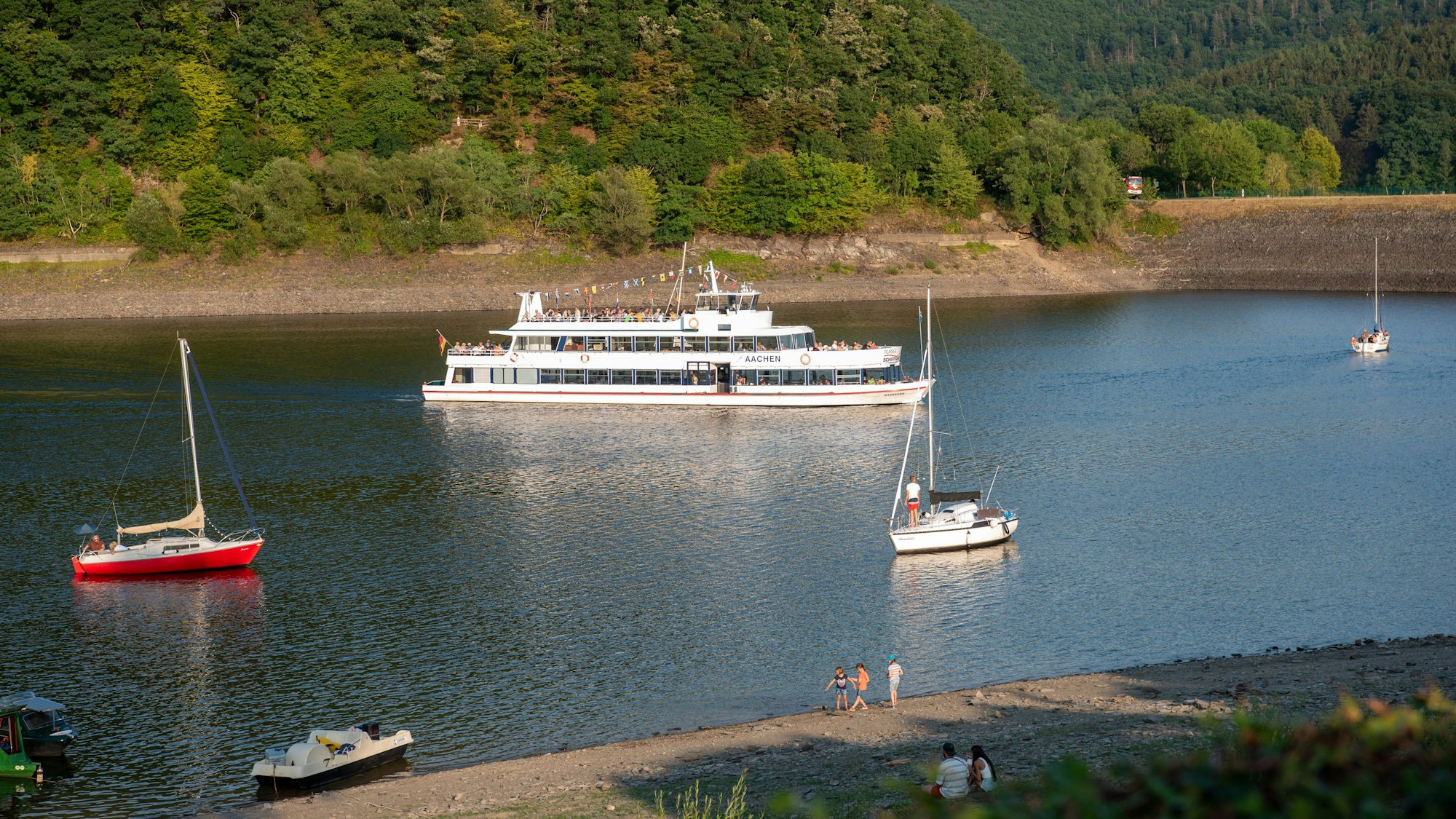 Auf dem Rursee fahren ein größeres Schiff und einige kleine Boote.